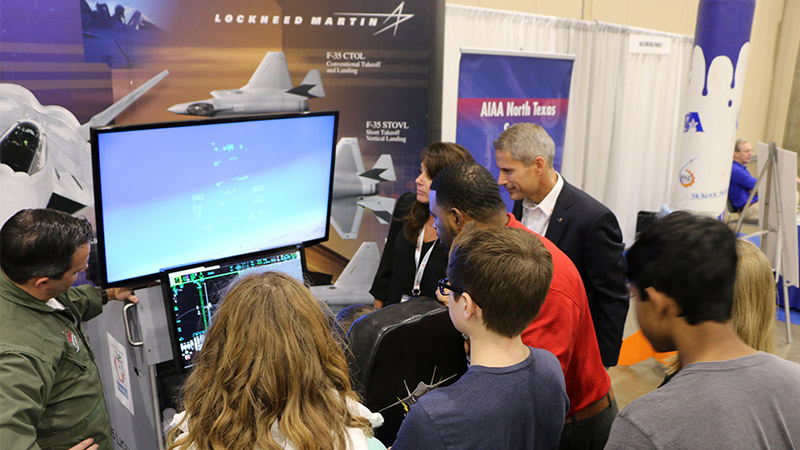 People viewing a flight simulation at a lockheed martin exhibition booth.