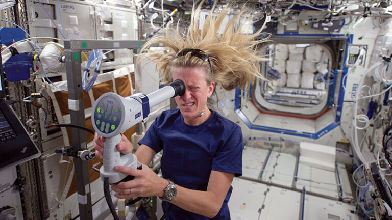Female astronaut using a handheld device inside the international space station, her hair floating in zero gravity.