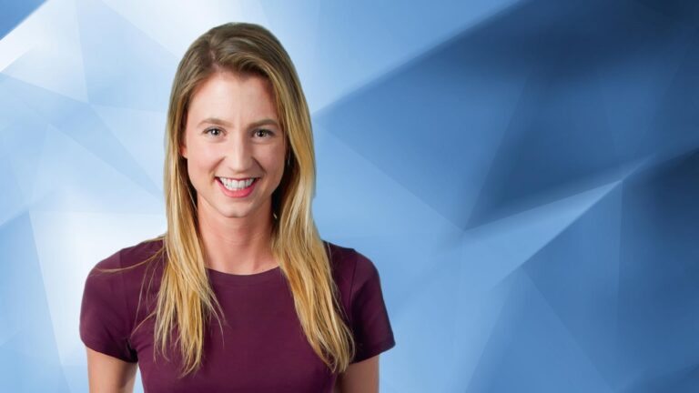 A woman with long blonde hair, wearing a purple shirt, smiles against a blue geometric background.
