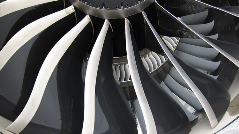 Close-up view of a jet engine's turbine blades and front fan assembly.