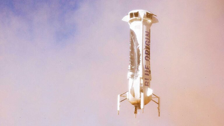 A rocket labeled "Blue Origin" descends vertically against a hazy sky, dust visible at its base during landing.