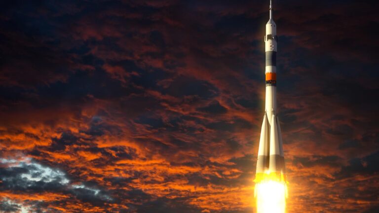 A rocket launching into the sky against a dramatic backdrop of red and orange clouds.