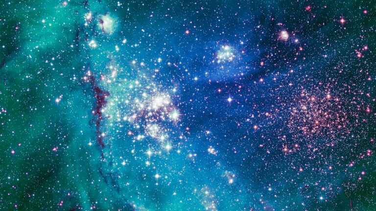 A vibrant, colorful cosmic scene showing numerous stars, nebulae, and space dust with shades of blue, green, pink, and purple against the blackness of space.