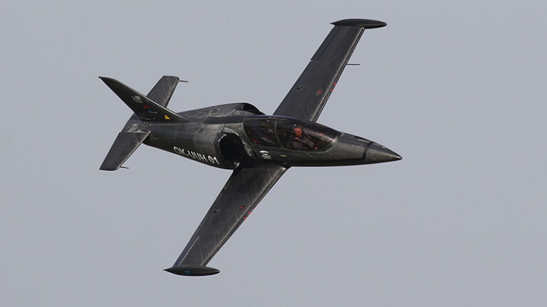 A black l-39 albatros jet in flight against a clear sky, showing its top side with visible cockpit and registration marks.