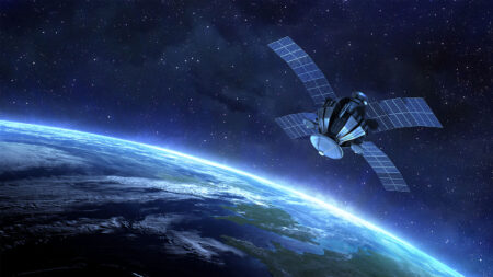 A satellite with solar panels orbits Earth against a backdrop of space. The planet's curve and atmospheric layers are visible below.