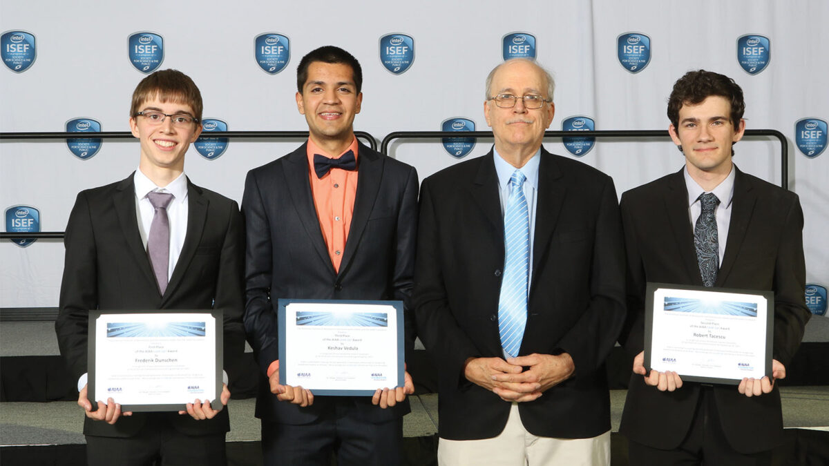 Four people stand in a row, three holding awards, at an event with an ISEF backdrop.