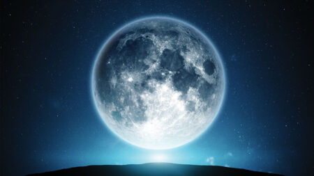 A bright full moon rises over a dark horizon, illuminating the night sky dotted with stars.