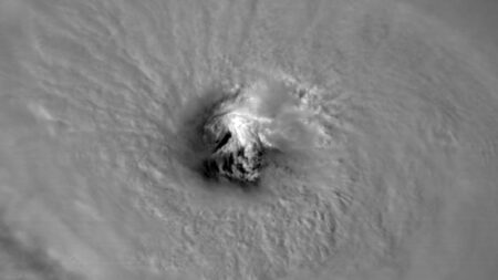 A satellite image of a hurricane's eye, displaying a clear, circular center surrounded by intense, swirling clouds.