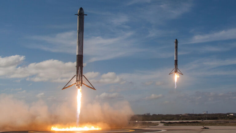 Industry disruption, transformation continue into fourth year Two rockets are vertically landing on designated platforms amidst clouds of smoke, with clear skies in the background.