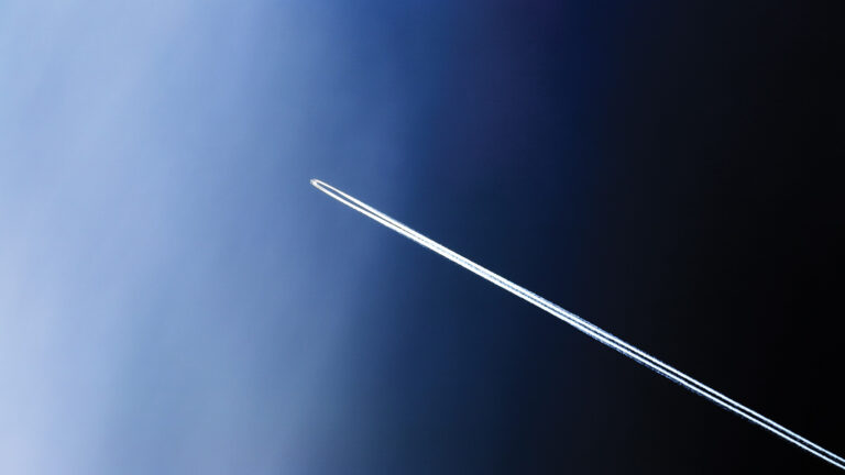 A jet aircraft leaves a contrail across a gradient sky transitioning from light blue to dark.