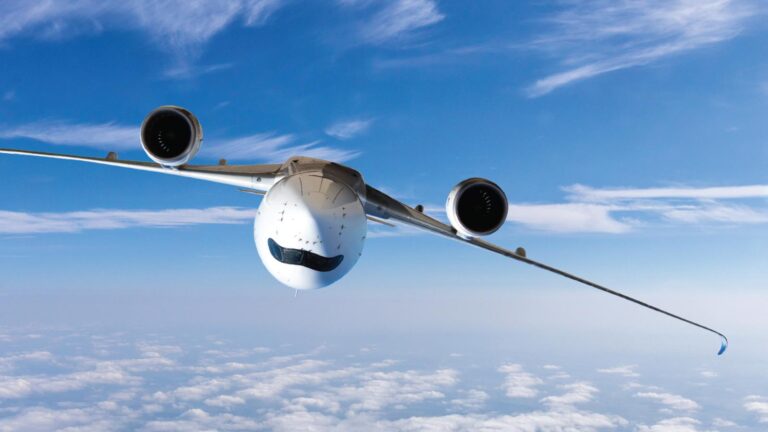 A large white aircraft is flying high above the clouds, viewed from below with the blue sky in the background.
