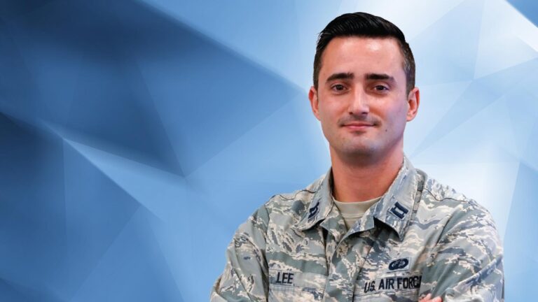 A person in a military uniform with "U.S. Air Force" and a name badge reading "LEE" stands with arms crossed in front of a geometric blue background.