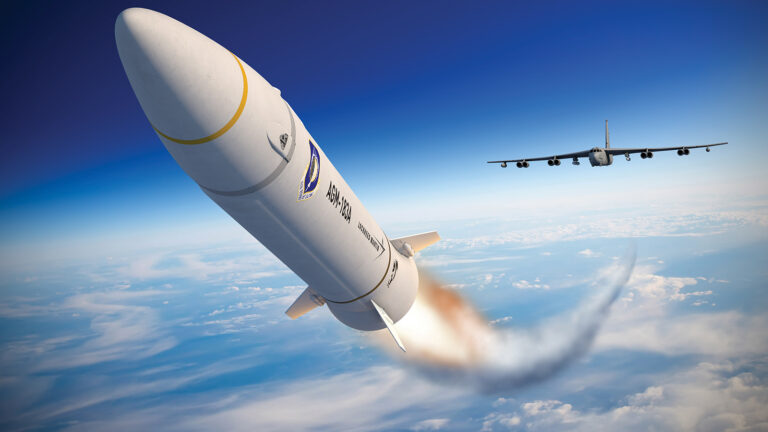 A large missile is being launched into the sky, leaving a trail of smoke, with a military aircraft flying nearby. The sky is clear with some clouds below.