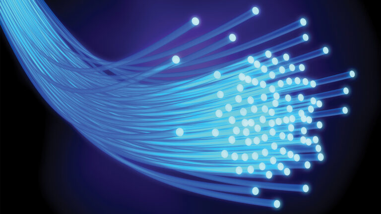 Image of multiple blue fiber optic cables emitting light on a dark background.