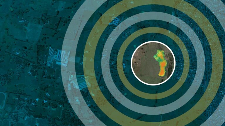 Aerial image with concentric circles centered on a thermal map marking a specific location. Surrounding terrain features and human-made structures are visible in the background.