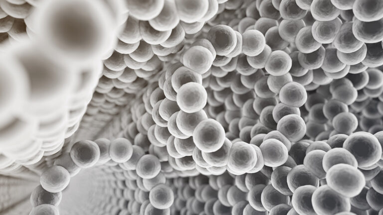 Microscopic view of a dense cluster of spherical nanoparticles forming interlocking patterns in a grayscale color scheme.