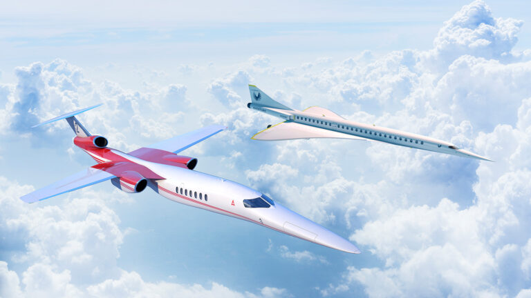 Two sleek, futuristic jets are flying above the clouds in a bright blue sky. The jet in the foreground is red and white, while the jet in the background is white and silver.