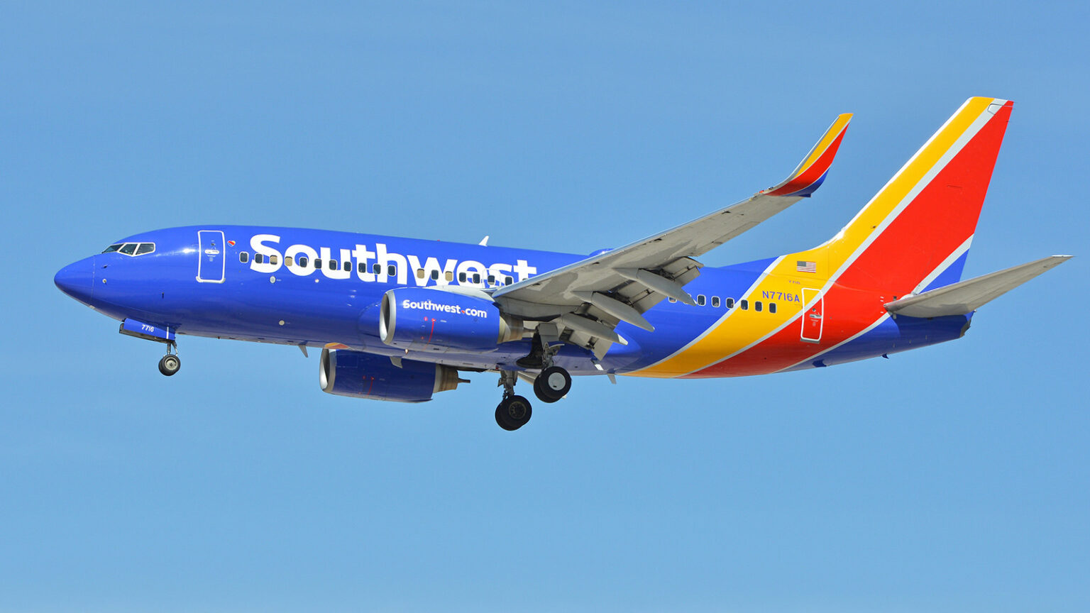 A Southwest Airlines plane with blue, red, and yellow livery is mid-flight against a clear blue sky.