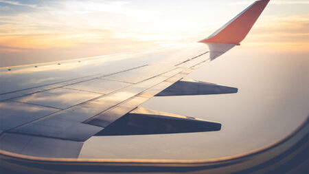 View from an airplane window showing a wing and winglet during flight with a sunset sky in the background.