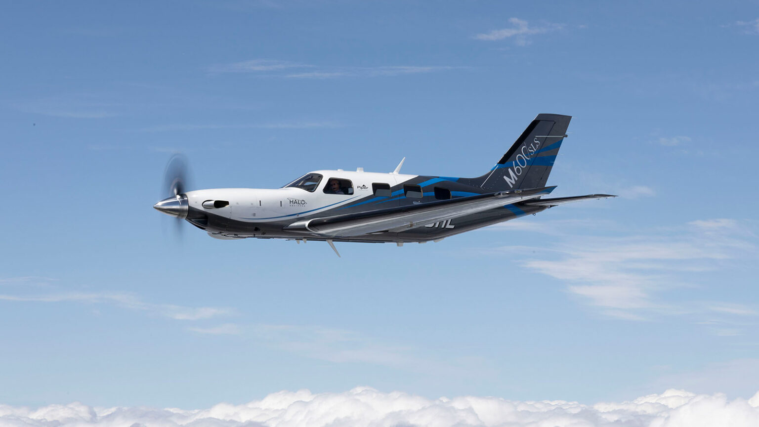 A single-engine, propeller-driven airplane flying against a backdrop of blue sky and scattered clouds.