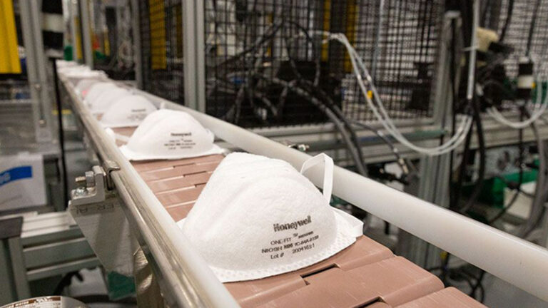A conveyor belt in a factory transports N95 respirator masks.
