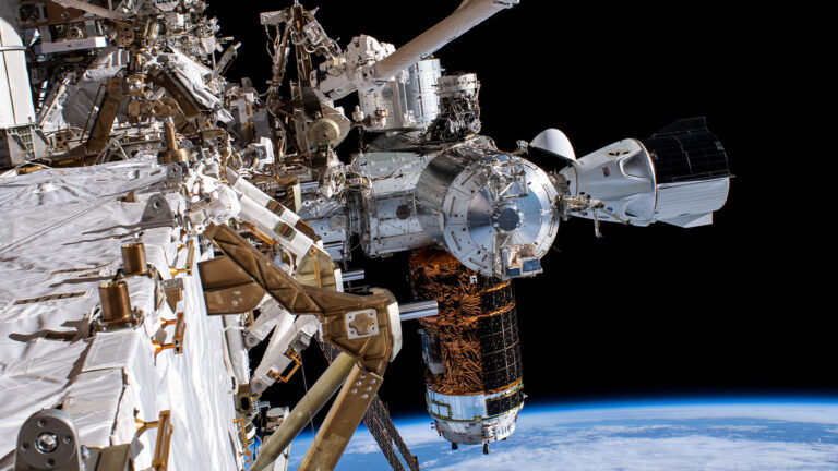 A detailed view of the International Space Station's exterior components with Earth visible in the background.
