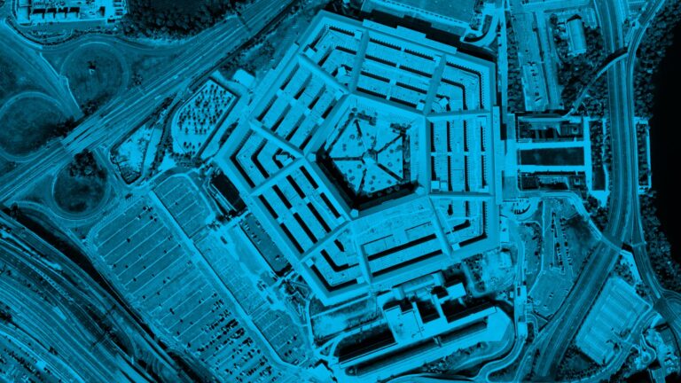 Aerial view of the Pentagon building, a large five-sided concrete structure, with surrounding roads and parking lots, captured in a blue monochrome filter.