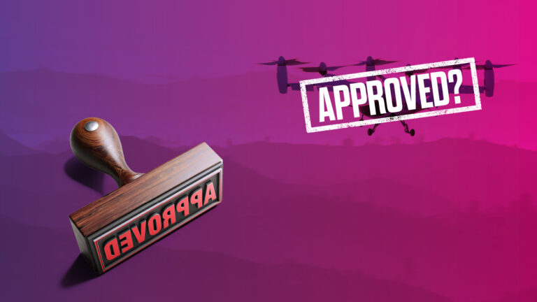 A wooden stamp labeled "APPROVED" is angled towards the viewer with the word "APPROVED?" in bold white letters against a pink and purple background featuring a silhouetted helicopter.