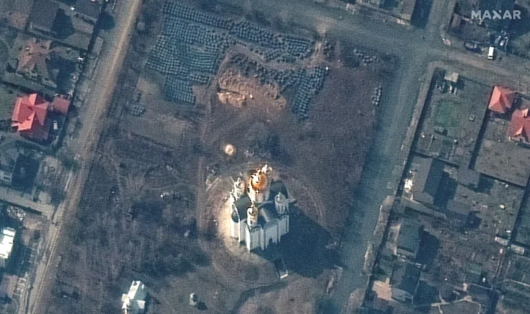 Aerial view of a white building with golden domes surrounded by a residential area with houses and roads.