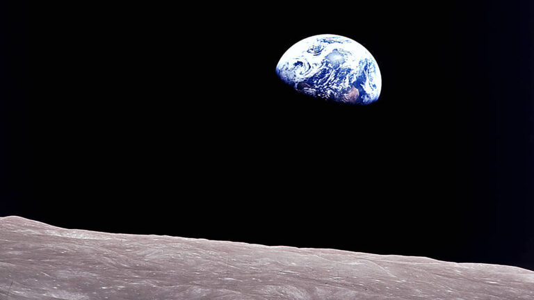 Photograph of Earth rising above the horizon of the Moon, captured against the backdrop of space.
