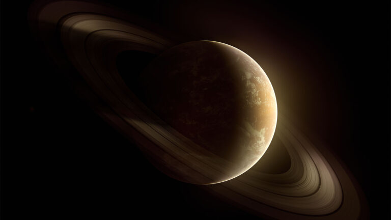 An image of a planet with rings, partially illuminated against a dark background.