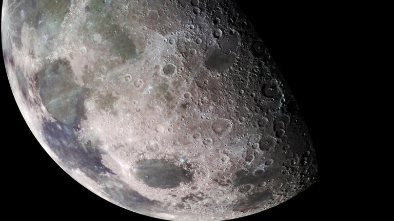 Close-up of the moon’s surface showing its craters, maria (dark plains), and a rugged, uneven texture against the blackness of space.