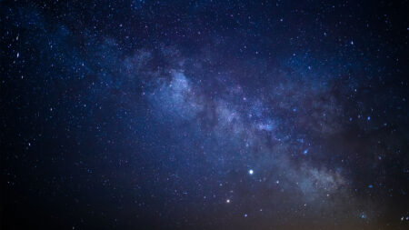 A clear night sky filled with stars and a prominent section of the Milky Way galaxy visible.