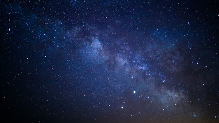 A clear night sky filled with stars and a prominent section of the Milky Way galaxy visible.