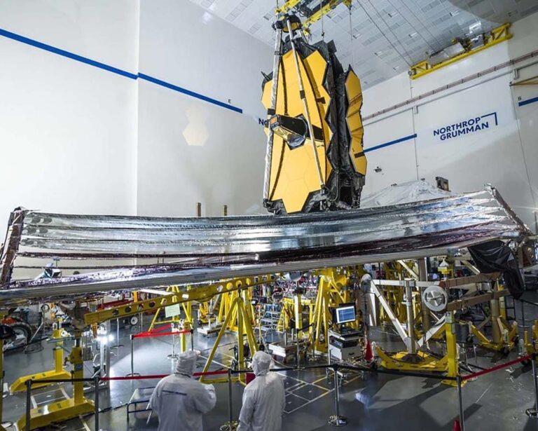 Technicians work on the James Webb Space Telescope, which is partially assembled with its sunshield deployed, inside a Northrop Grumman facility.