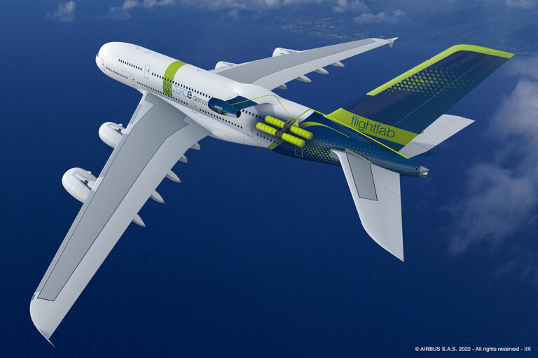 An Airbus aircraft with "flightlab" branding flies over the ocean displaying green and blue accents and visible technological modifications on its body and tail.