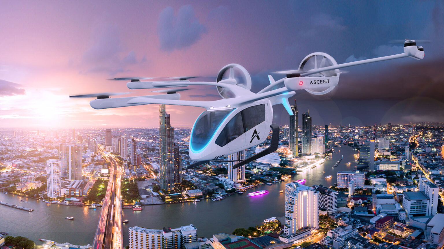 A white futuristic flying car with multiple rotors hovers over a cityscape at sunset, with tall buildings and a river below.