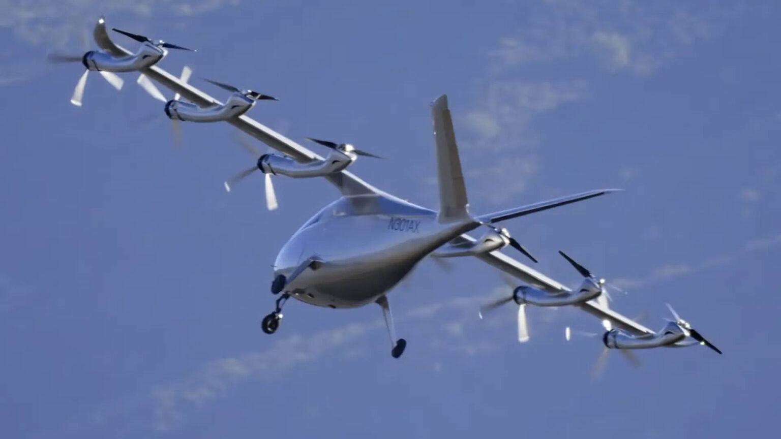 Electric Vertical Takeoff and Landing (eVTOL) aircraft in mid-flight against a background of clear sky and mountains.