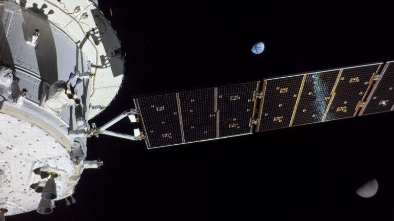 A segment of a space station with a solar panel extends into space. The Earth and Moon are visible in the background against the blackness of space.