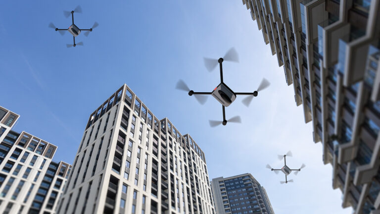 Several drones fly between high-rise buildings in a cityscape under a clear, blue sky.