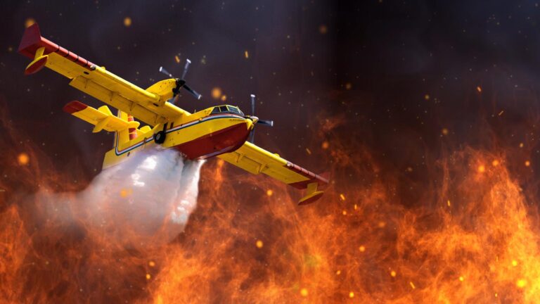 A yellow and red firefighting aircraft releases water over a large blaze, attempting to extinguish the fire below.