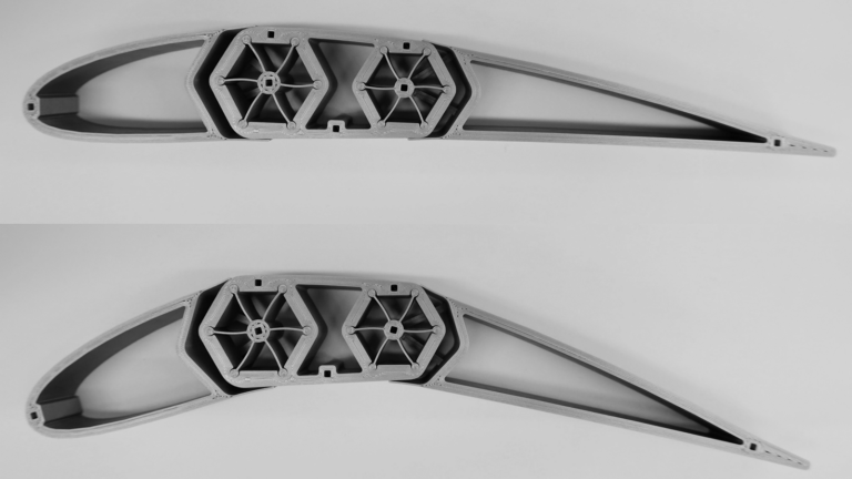 Two identical, gray, 3D-printed mechanical parts displayed on a plain background, each featuring geometric internal structures for support.