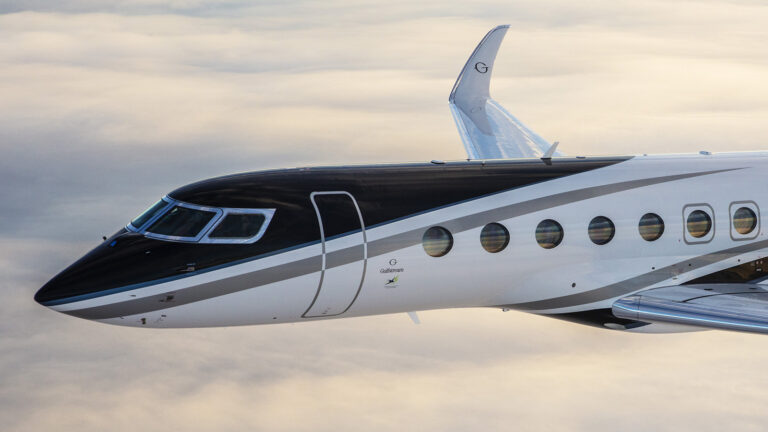 A black and white private jet is flying above the clouds, showing its side profile and four cabin windows along with the tail fin.