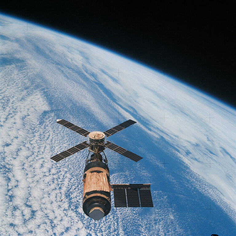 Celebrating 50 years since the launch of Skylab and other anniversaries A space station with solar panels orbits above Earth's atmosphere, with the vast blue planet and clouds visible in the background.