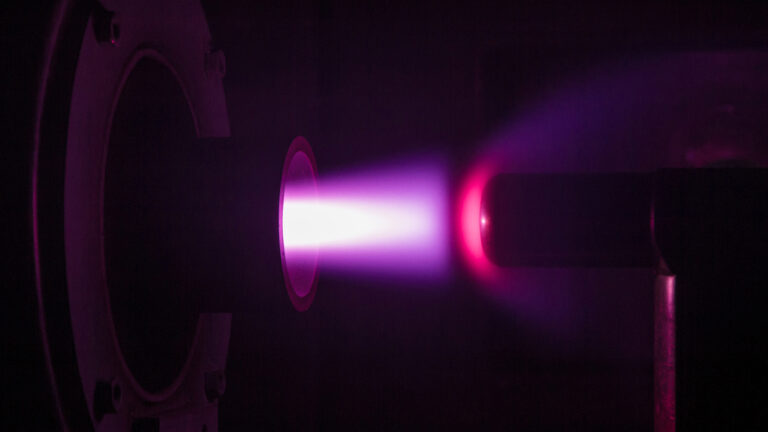 A purple plasma beam emits light in a dark setting, highlighting a cylindrical object directed towards the beam.
