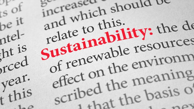 A close-up of a printed page with the word "Sustainability" highlighted in red. Surrounding text is in black and discusses topics related to renewable resources and their environmental impact.