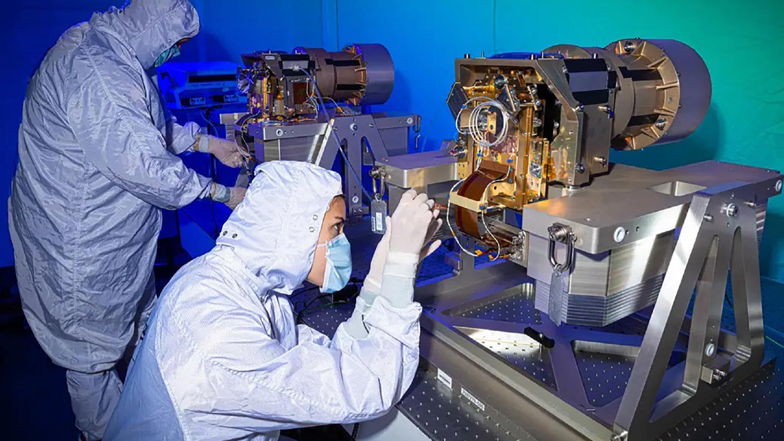 Two technicians crouching in front of spectrometer instruments