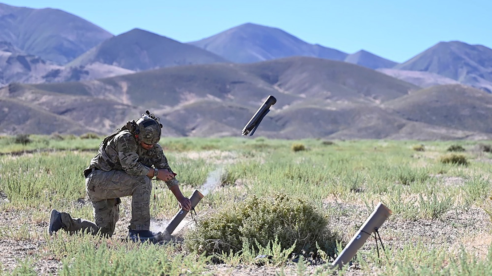 U.S. Navy operator kneels in a field, releasing a Switchblade drone
