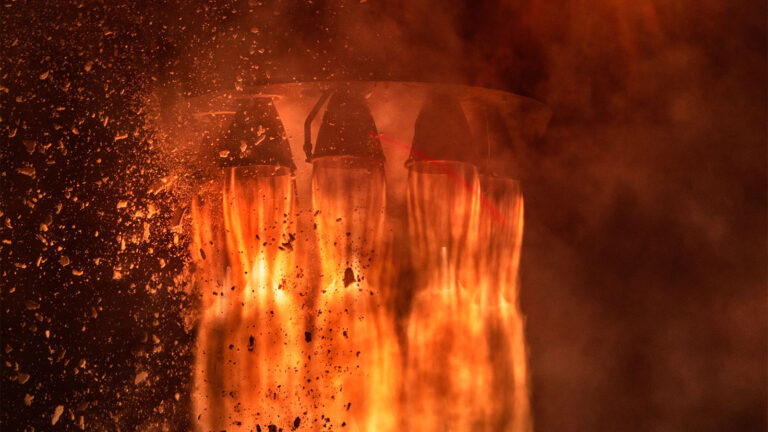 Close-up view of rocket engines emitting flames and debris during a fiery launch sequence.
