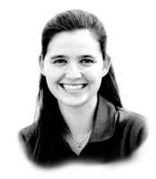 Black and white photo of a smiling woman with long, dark hair, wearing a collared shirt. She is looking directly at the camera.